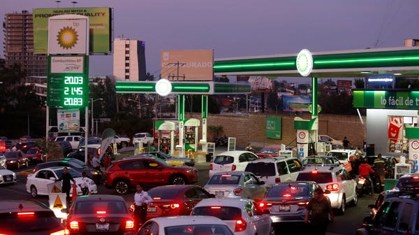 People wait in line to buy gasoline in...