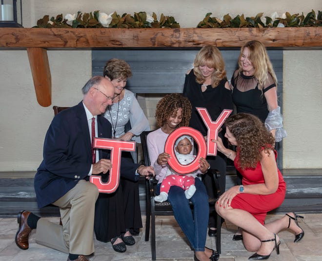 "Joy" is the theme of the 2019 Mary’s Shelter gala. Pictured are, from left, John Glynn Jr., Florence Oreiro, Angie Leggio, Madeleine Greenwood and Gina Thompson. Seated is Mary's Shelter resident Wilmene with her daughter, Khalani.