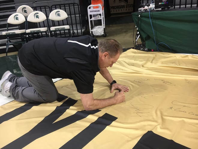 Michigan State men's basketball coach Tom Izzo signs a banner in remembrance of Purdue fan Tyler Trent ahead of the men's basketball game against Purdue on Jan. 8, 2019.