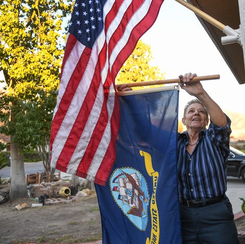 Phyllis Seleska hangs a Navy flag in the front of...