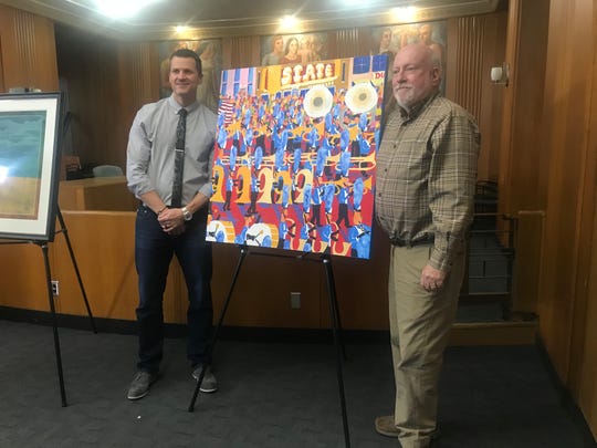 Sioux Falls-based artist Rodger Ellingson and Mayor Paul TenHaken pose for photographs next to Ellingson's “The Band,” a bright, colorful canvas painting depicts the Festival of Bands with musicians marching in front of the State Theater.