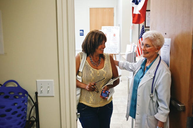 Neighborhood Health Clinic founder Nancy Lascheid, right, welcomes Debra Knight as she enters the clinic in Naples on Thursday, Sept. 12, 2013.