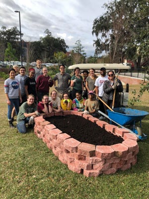 Student volunteers celebrate the first built garden bed.