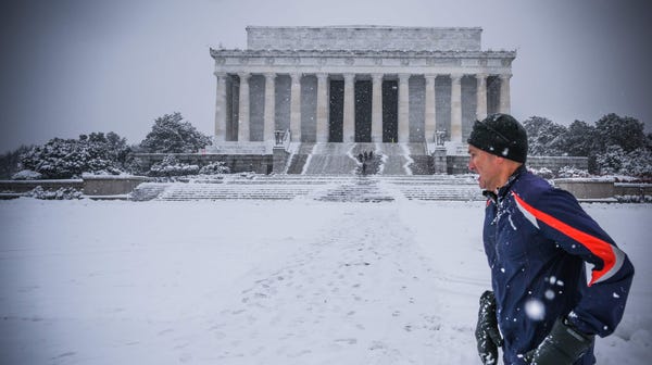 A jogger runs by the Lincoln Memorial as snow...
