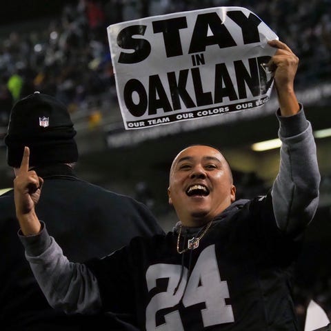 An Oakland Raiders fan holds a sign reading "stay...