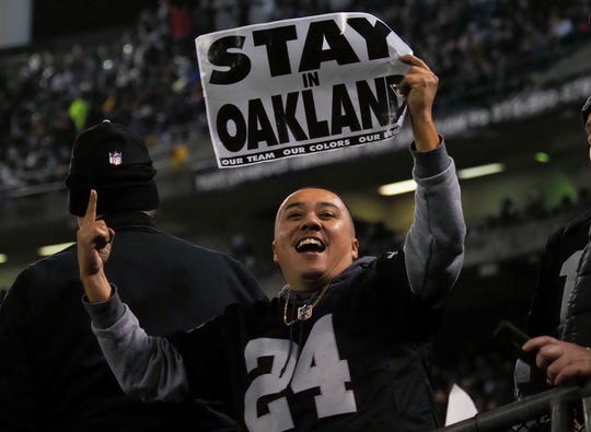 Um fã de Oakland Raiders detém uma leitura de sinal