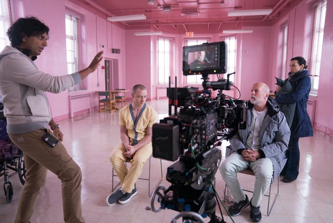 M. Night Shyamalan, left, goes over a scene with James McAvoy and Bruce Willis on the "Glass" set.