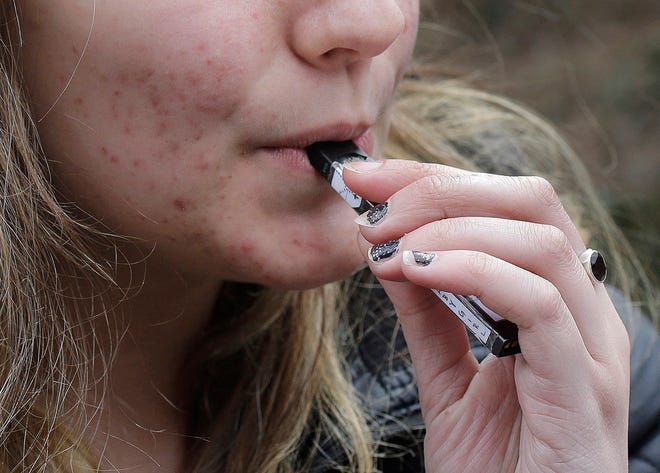 A high school student uses a vaping device