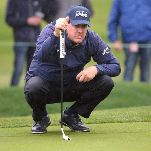 Phil Mickelson lines up a putt on the sixth green...