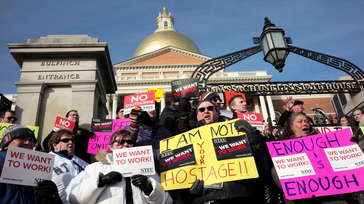 Federal employees are pictured protesting the government shutdown in front of the Statehouse in Boston.