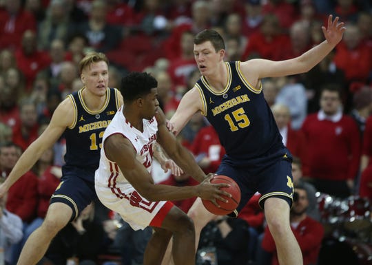 Badgers guard Khalil Iverson dribbles against Wolverines forward Ignas Brazdeikis, left, and center Jon Teske at the Kohl Center on Saturday.