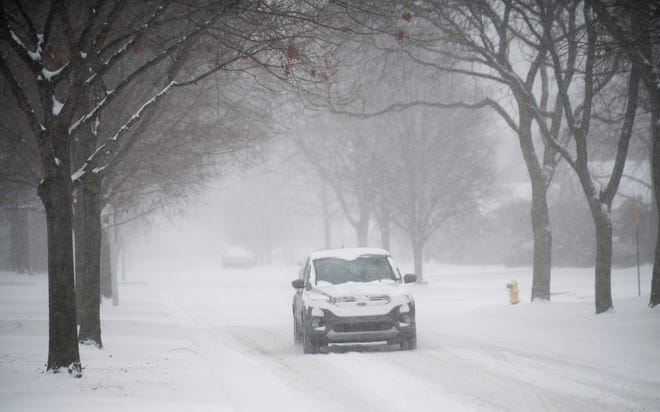 A vehicle drives slowly along a snowy Fairholme Road on Saturday morning in Grosse Pointe Woods.