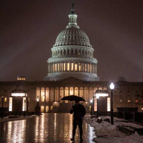 Snow falls on the Capitol as the partial...