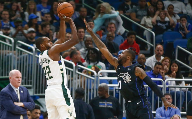 Khris Middleton of the Bucks hoists up an outside shot over Magic forward Jonathan Simmons during the first quarter on Saturday night.