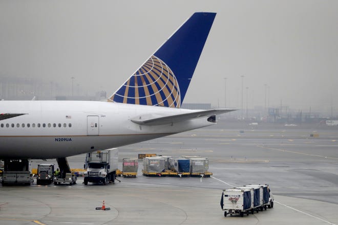 A luggage cart rolls near a United Airlines jet at Newark Liberty International Airport, Tuesday, in Newark, New Jersey. A flight leaving the airport over the weekend made an emergency stop in Canada, stranding passengers for hours.