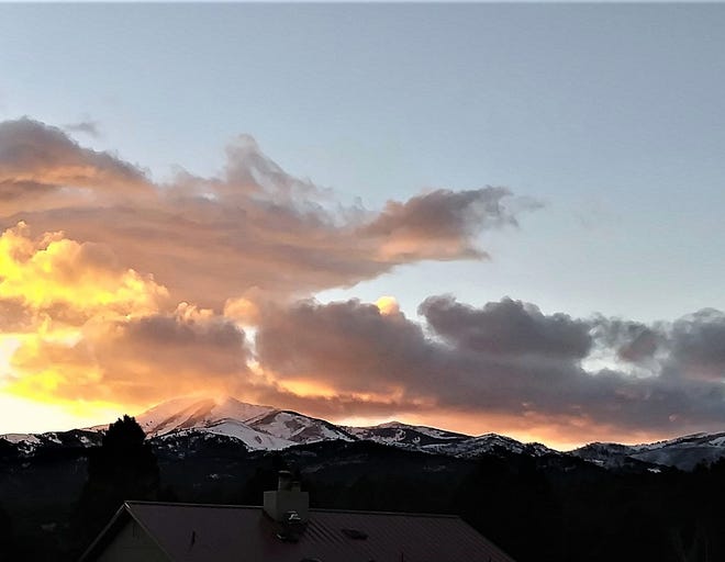 Sierra Blanca Peak is bathed in sunlight bouncing off clouds as the sun sets in Ruidoso.