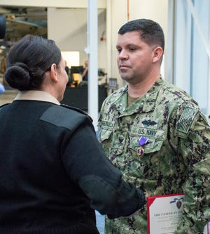 Rear Adm. Tina Davidson, left, presents Navy Hospital Corpsman 1st Class Eduardo Sanchez-Padilla the Purple Heart during a ceremony at the National Naval Aviation Museum in Pensacola on Wednesday, January 23, 2019.  Sanchez-Padilla was wounded in Afghanistan in 2009.