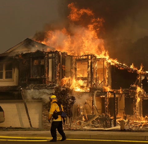 A firefighter walks near a flaming house in Santa...