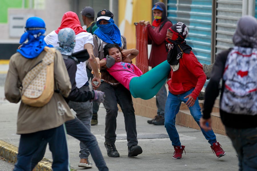 Several people help a young woman after fainting from inhaling tear gas, Wednesday, during a protest against the Government of the Venezuela President Nicolas Maduro. Thousands demonstrated  in the 23 states of the country and the Capital District against Nicolas Maduro.