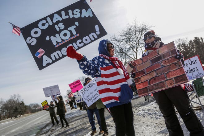 In a photo from January 2019, Elizabeth Fohey, 72, of Troy, Michigan, holds up a sign at a Women for Trump event, a “Build the Wall” rally, in Bloomfield Hills. Fohey says she loves her country and "what's happening now scares me. Socialism doesn't work, capitalism does."