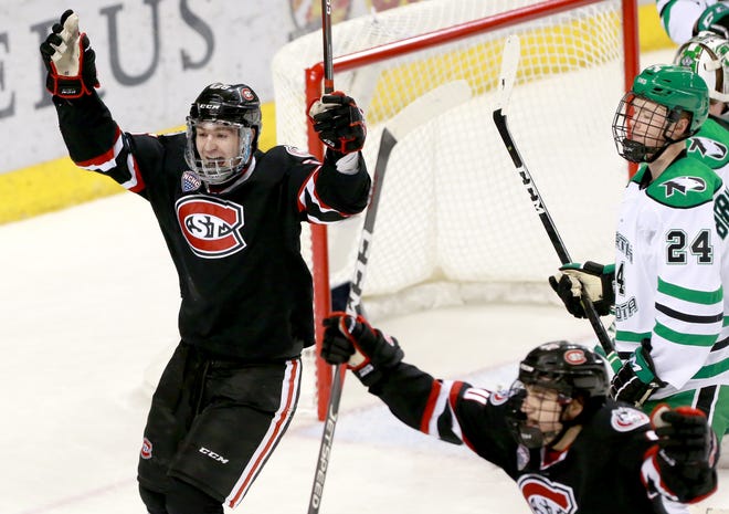 St. Cloud State's Nick Perbix and Jon Lizotte celebrate the Huskies' first goal in the second period against North Dakota in Friday's NCHC game at the Ralph Engelstad Arena. UND's Jacob Bernard-Docker looks on.