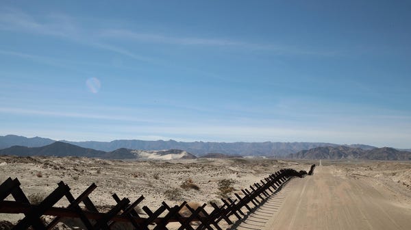 A steel barrier runs along the border of the...