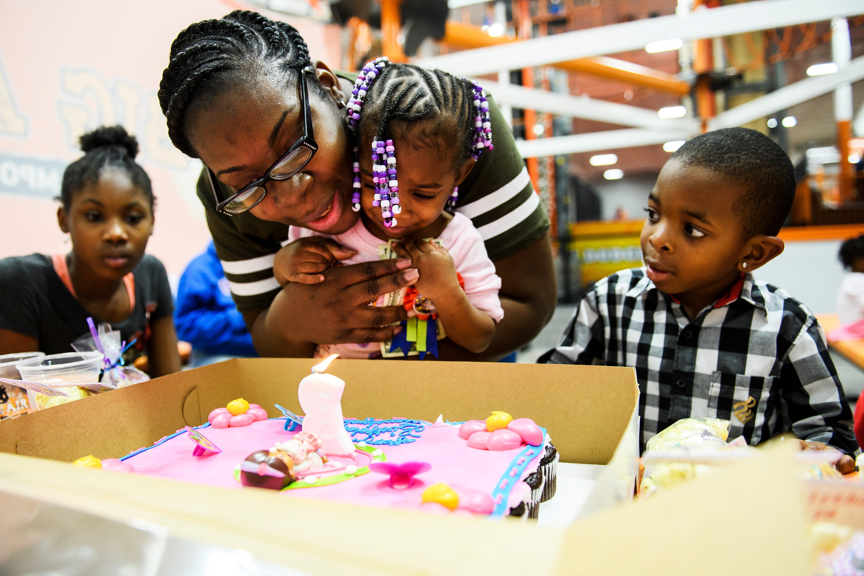 Tiffany Copeland holds her daughter Jenilya as she blows out the candles on her cake for her third birthday party at Big Air Trampoline Park on Saturday, Dec. 15, 2018.