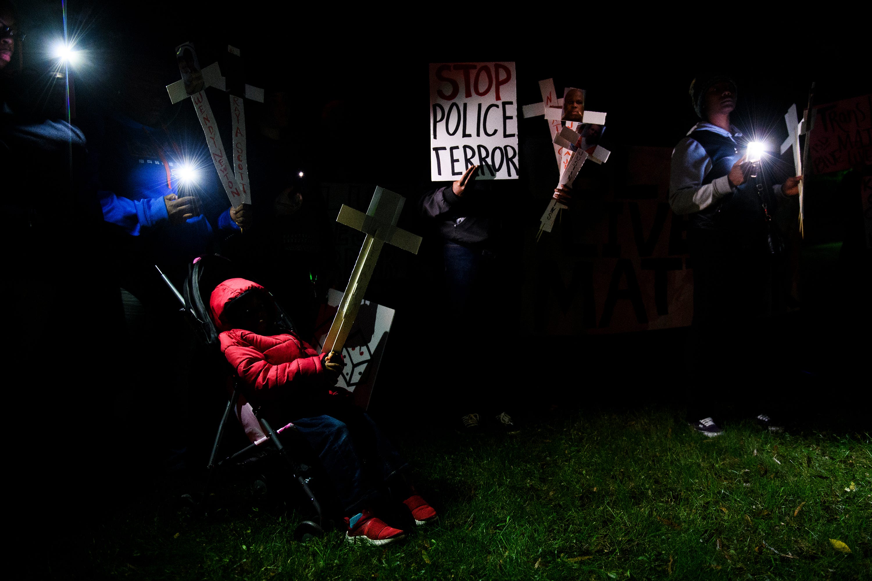 Jermier Massey, 6,  son of Jermaine Massey, holds a cross with his father's name and photograph on it during a protest march against police brutality outside of the law enforcement center on Monday, Oct. 22, 2018.