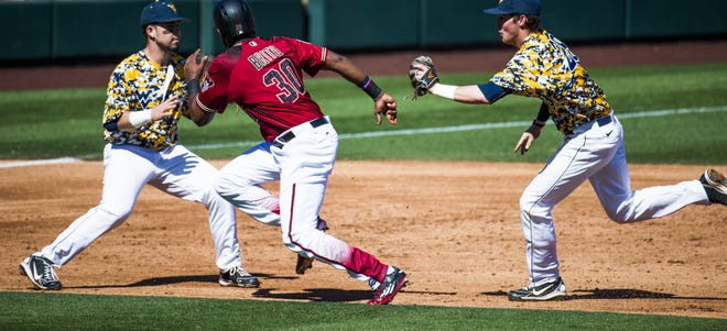 Arizona Diamondbacks Socrates Brito is squeezed by West Virginia University infielders Kyle Davis, left, and Cole Austin at Salt River Fields at Talking Stick, Monday, February 29, 2016. Brito was tagged out. Austin has since transferred to Arizona State.