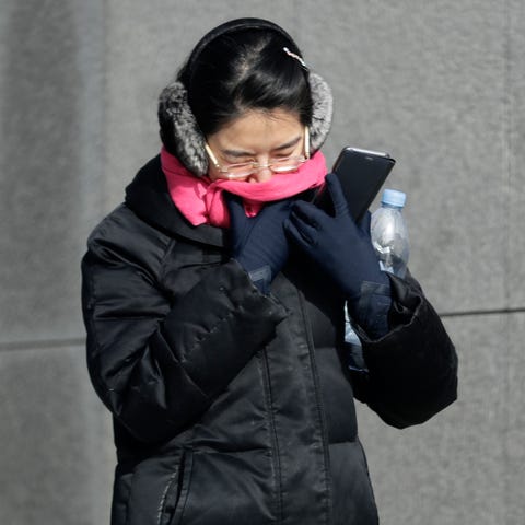 A woman is bundled up against the cold in...