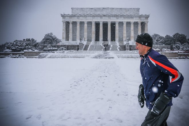 A jogger runs by the Lincoln Memorial as snow accumulates in Washington, D.C., on Jan. 13.