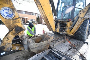 Miquel Cook, 21, a Detroit Water and Sewerage Department employee, straps down heavy equipment after working on a water main break on Renfrew in Detroit, Wednesday.