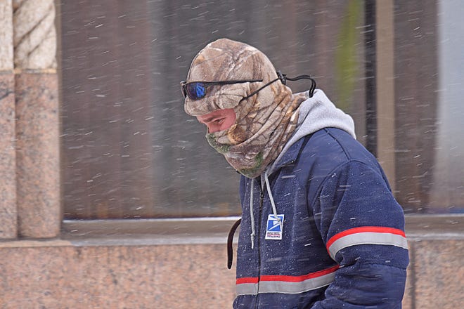A United States Postal Service worker braves high winds and sub-zero temperatures on his route Wednesday morning in downtown Mansfield.
