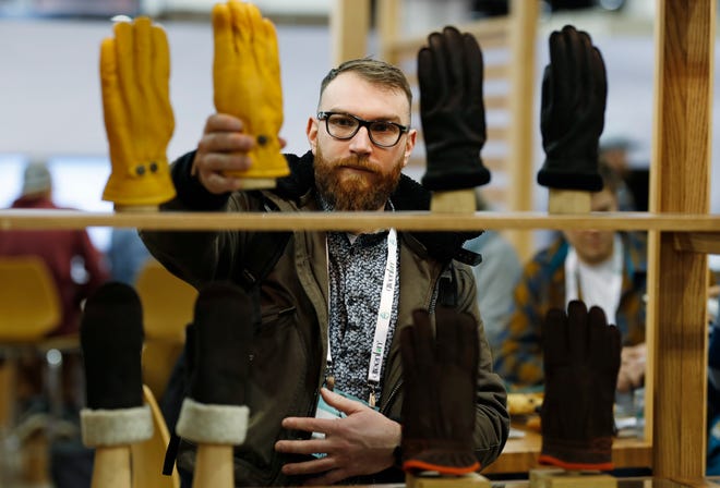 Theo Kerbourch of Ville St. Laurent, Quebec, Canada, looks over gloves for sale in the Hestia exhibit at the Outdoor Retailer & Snow Show Wednesday, Jan. 30, 2019, in the Colorado Convention Center in Denver. Major players in the outdoor industry have joined more than 900 other exhibitors to show their wares to the more than 25,000 attendees expected for the weekend event. (AP Photo/David Zalubowski)