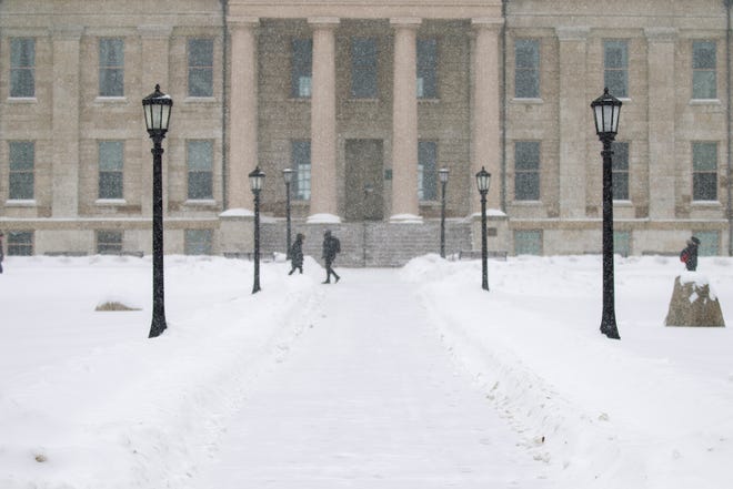 Students walk past the Old Capitol Building as snow falls on Thursday, Jan. 31, 2019, in downtown Iowa City, Iowa.