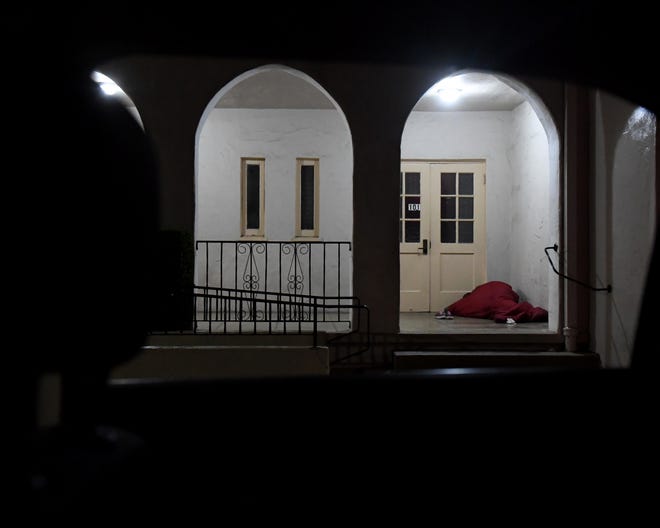 A homeless person sleeping in a church walkway.