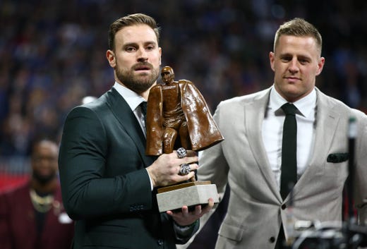 Houston Texans player J.J. Watt, right, presents the Walter Payton Man of the Year trophy to Philadelphia Eagles player Chris Long before Super Bowl LIII/
