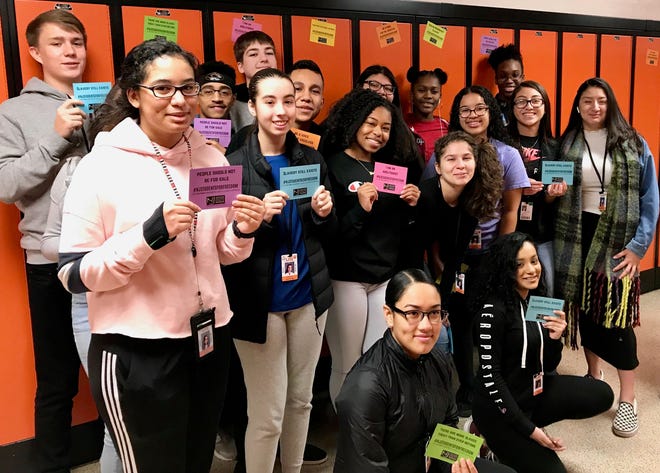 Students from one of Derrick Potts’ world history classes showing the locker magnets they distributed to help raise awareness about human trafficking.