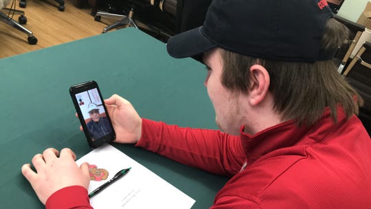 New Milford lineman Emmett McElroy gets a FaceTime call from Ed Marinaro at his Signing Day ceremony. McElroy is the first New Milford player to go to Cornell since Marinaro.