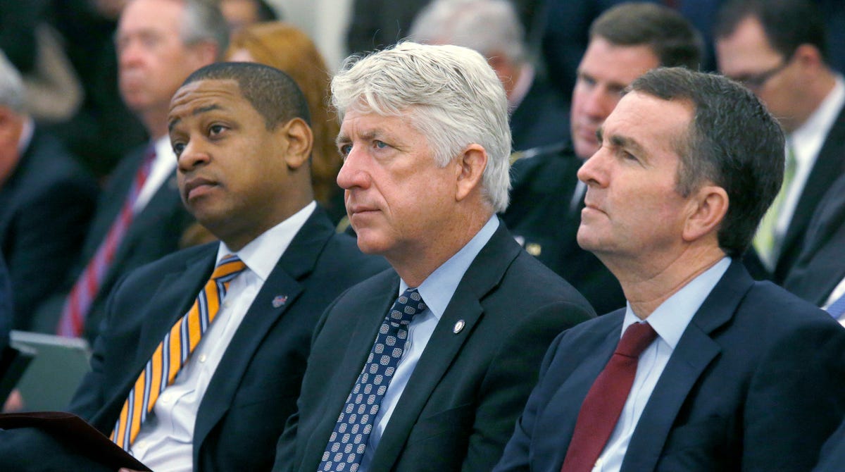In this Dec. 18, 2017 file photo, from left, Lt. Governor-elect Justin Fairfax, Attorney General-elect Mark Herring and Governor-elect Ralph Northam listen as Virginia Governor Terry McAuliffe addresses a joint meeting of the House and Senate money committees at the Pocahontas Building in Richmond, Va.
