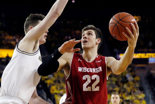 Wisconsin forward Ethan Happ tries to find space for a shot against the tight defense of Michigan center Jon Teske.
