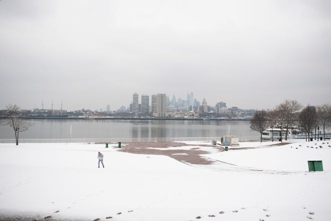 A man exercises along the Camden Waterfront following snowfall in the region Monday, Feb. 11, 2019 in Camden, N.J.