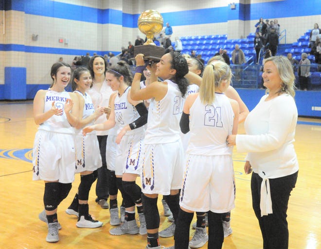 Merkel sophomore Alyssa White (20) holds up the Lady Badgers' bi-district trophy after beating Coleman 49-33 Monday, Feb. 11, 2019, at Winters High School.