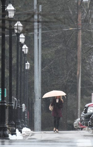 A woman uses an umbrella to stay dry Tuesday morning as the rain falls during her walk up Walnut Street.