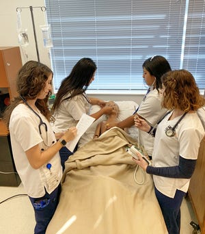 Nursing students (from left) Makenna Gorman, Emely Diaz, Kaitlyn Flores and Riley Mulhern practice assessing and admitting "Pedi," their 5-year-old high fidelity pediatric simulator in the Lorenzo Walker Technical College Simulation Lab.