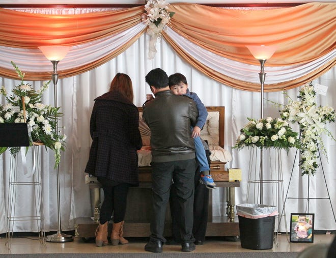 The family of Bill Thao stood next to his tiny casket at his visitation Jan. 2, 2015, at Lakeview Funeral Home, 9075 N. 76th St. Bill's father, Samboon Thao (right), holds Bill's little brother Magic Thao, 3. His wife, Suabna Xiong, is at left. Bill's grandmother is in front of them stroking the boys head in the casket.
