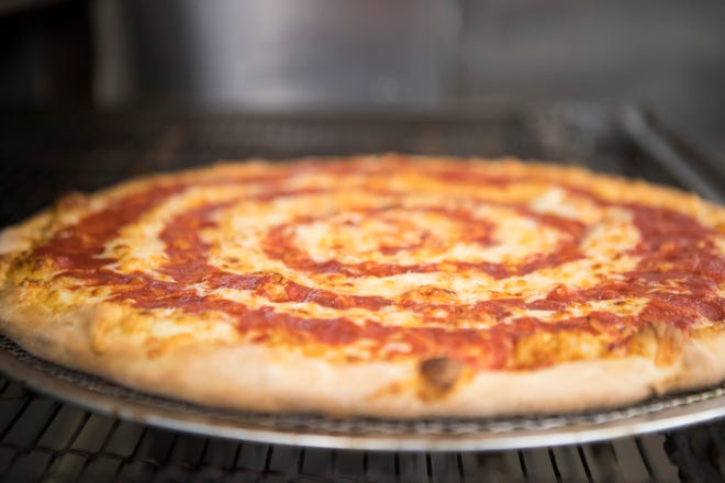 A finished Grotto Pizza cheese pizza appears from the oven at their Pennsylvania Avenue location in Wilmington. 