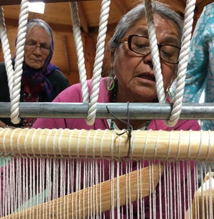 Lois Becenti sets the batter stick inside the wool warp on a weaving loom during the Crownpoint Spin Off at Navajo Technical University on Friday.