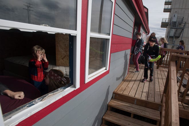 Polaris student Aron Jocobs, right, prepares to storm a house with his teammates while three-year-old Gavin Dembek pretends to be a zombie held up in an interior room with others during a zombie survival simulation on Thursday, Feb. 14, 2019, at the Poudre Fire Authority tarring facility in Fort Collins, Colo. In this simulation the team entering the house is tasked with collecting supplies scattered around the home while avoiding the zombie horde inside and around the house.