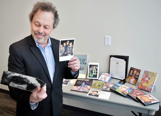 In this Thursday, Feb. 7, 2019, Curtis Armstrong, an actor, producer and writer, holds some of the 30-years of memorabilia from his career in film and television at Oakland University in Rochester, Mich. Armstrong, an alumnus of the university, has donated the material to Oakland University's archives.